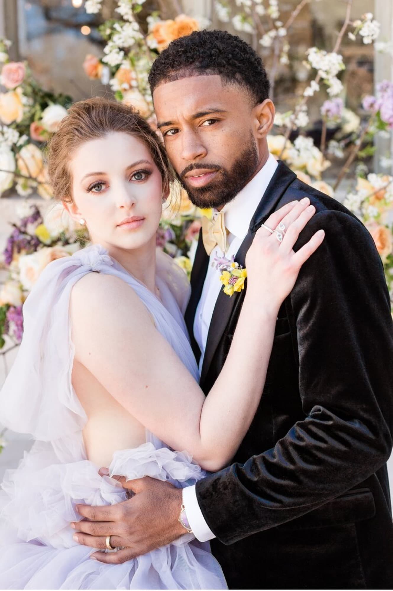 Abyon Ausar in black tie with a bride in a lilac gown outside a stone building