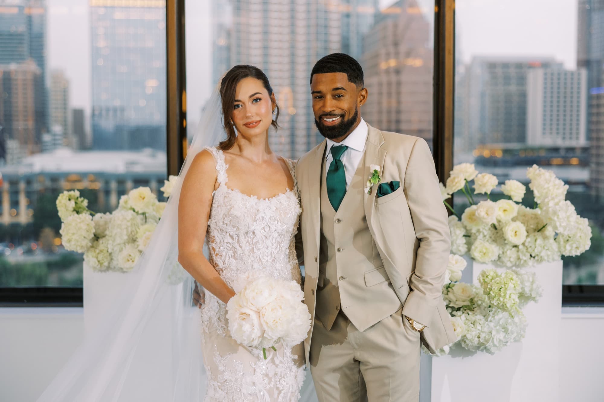 Abyon Ausar in a cream suit with a bride on a rooftop in daylight