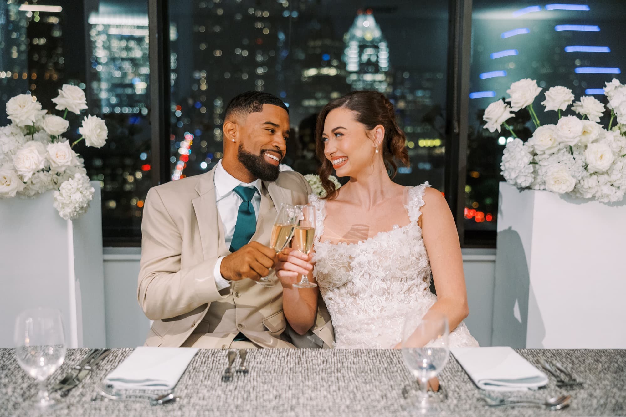 Abyon Ausar in a cream suit with a bride, Austin skyline lit behind them