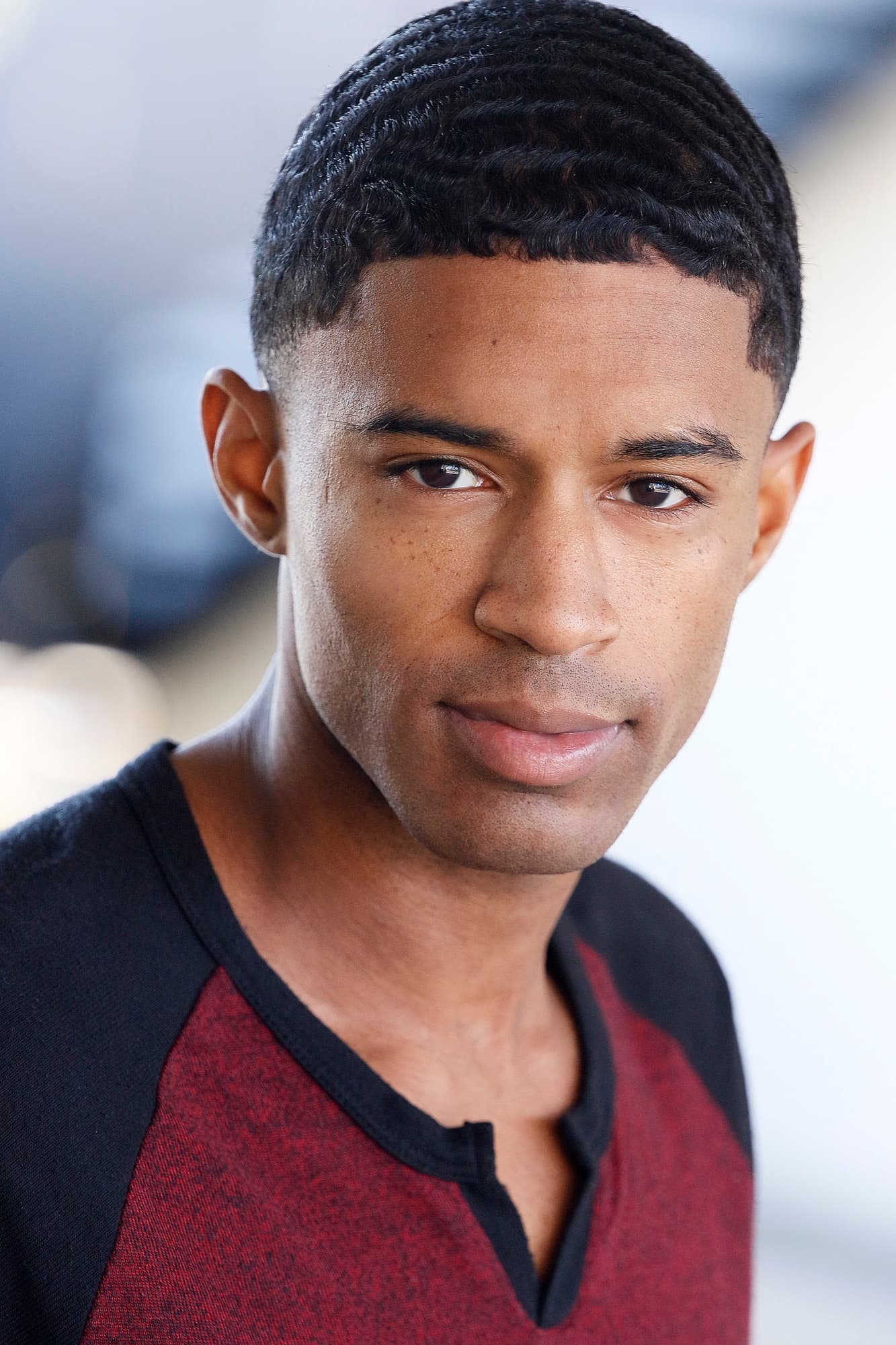 Smiling headshot of Abyon Ausar in a red plaid shirt