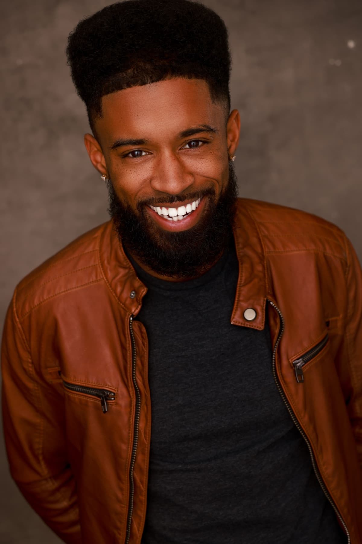 Smiling headshot of Abyon Ausar in a tan leather jacket