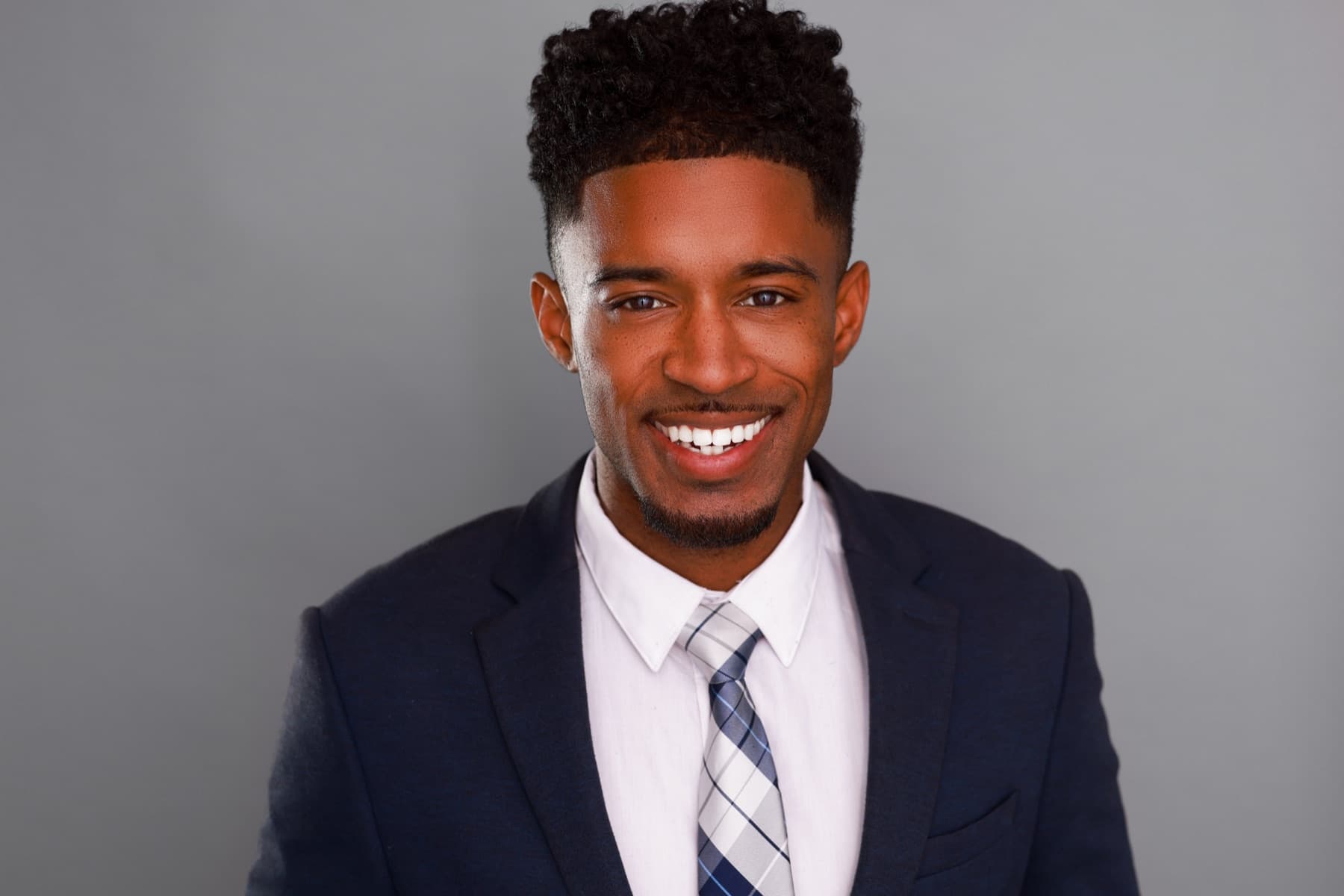 Smiling headshot of Abyon Ausar in a navy suit and tie