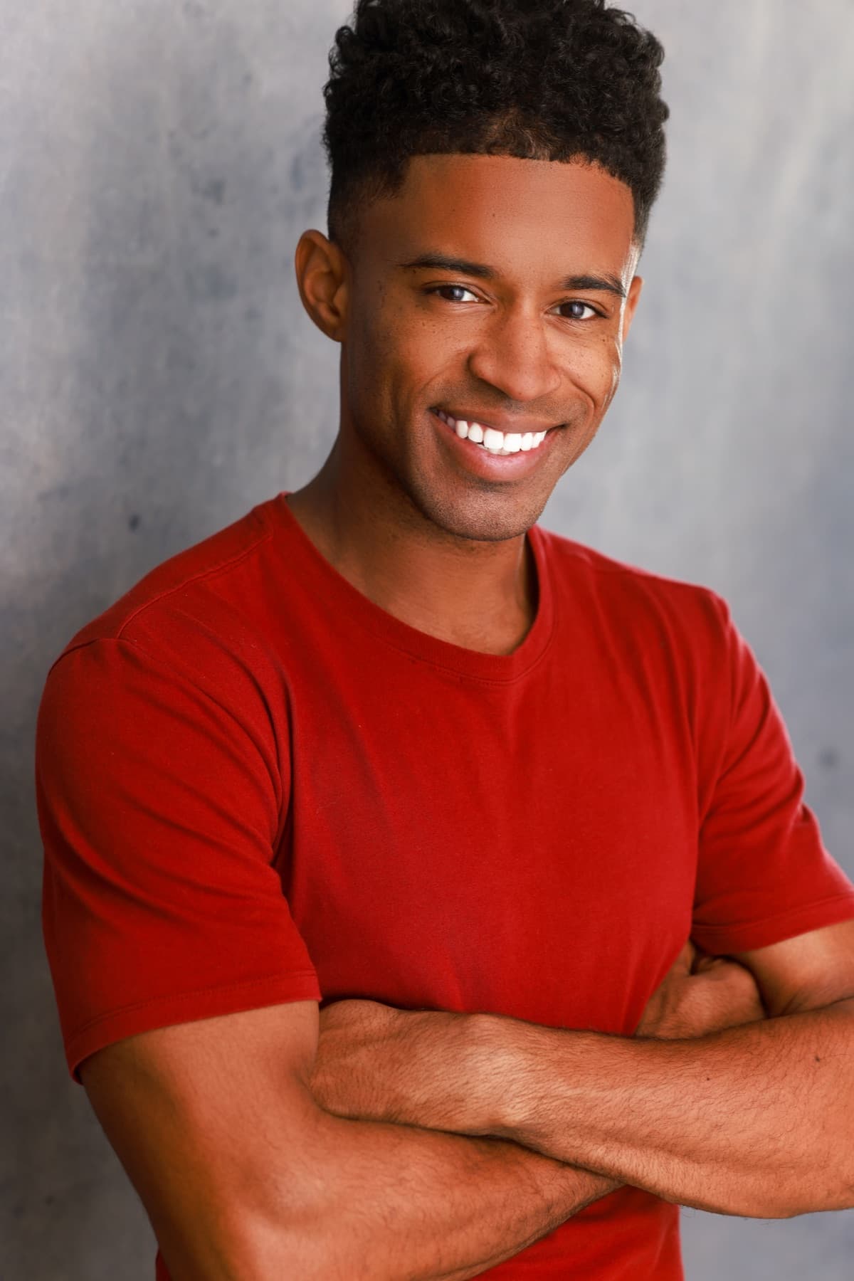 Smiling headshot of Abyon Ausar in a red tee, arms crossed