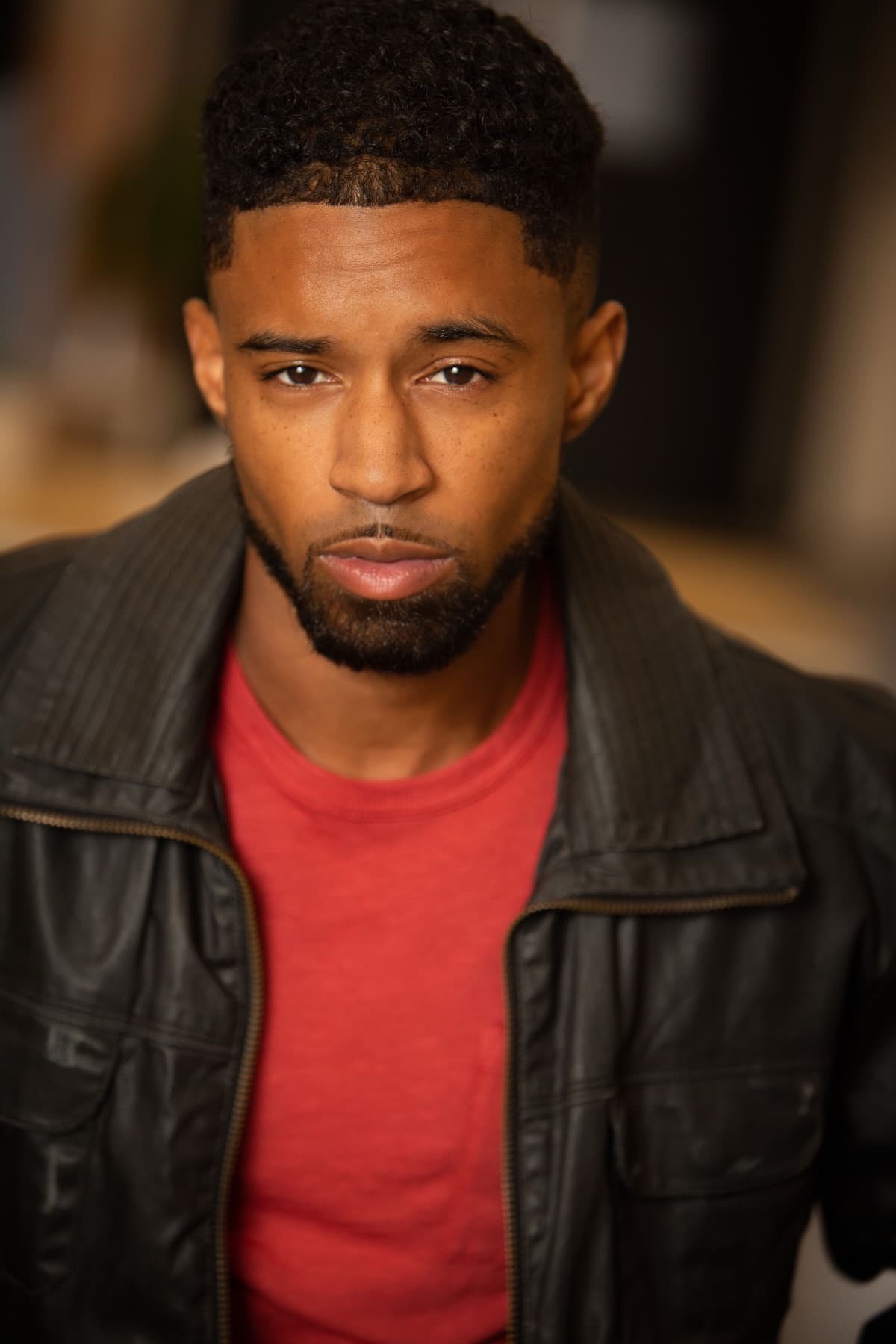 Moody headshot of Abyon Ausar in a brown leather jacket