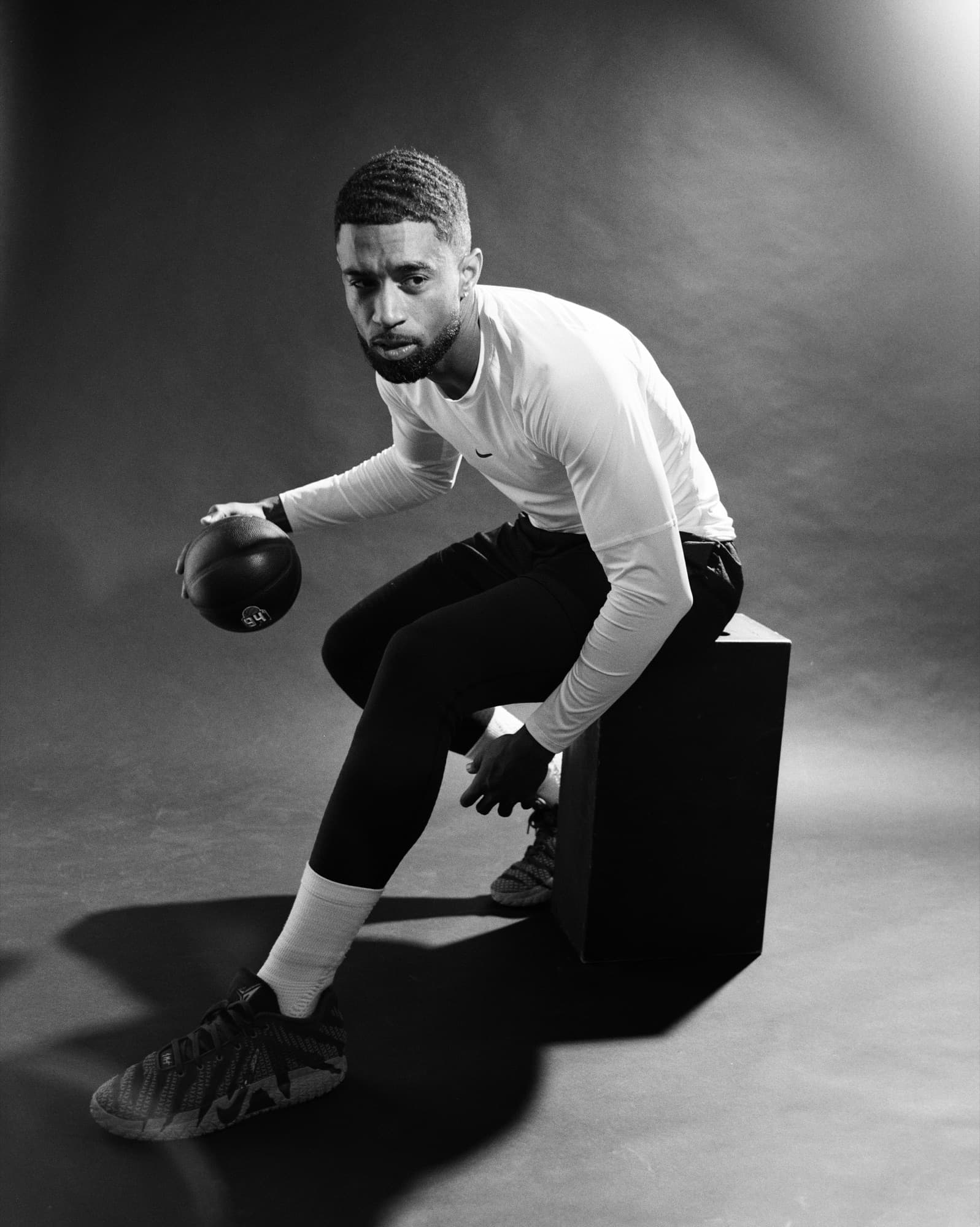 Black and white studio shot of Abyon Ausar crouched with a basketball